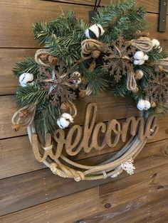 a welcome sign hanging on the side of a wooden wall with pine cones and snowflakes