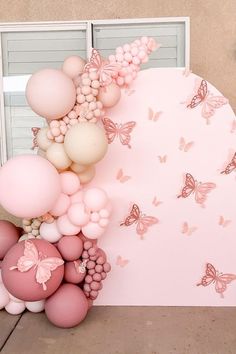 a bunch of balloons that are in front of a wall with butterflies on it,