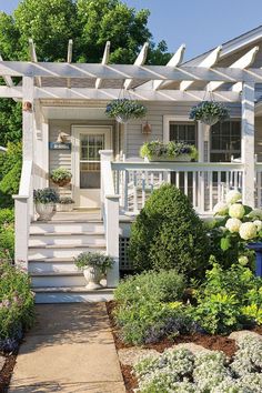 a white house with flowers and plants on the front porch