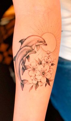 a dolphin and flowers tattoo on the arm