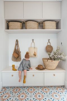 a little boy sitting on top of a white shelf next to baskets and purses