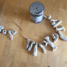 the letters spelled out in white clay are next to a can of paint on a wooden floor