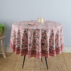 a round table with a red and white floral design on it next to a potted plant