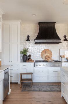 a kitchen with white cabinets and an oven above the stove, surrounded by wood flooring