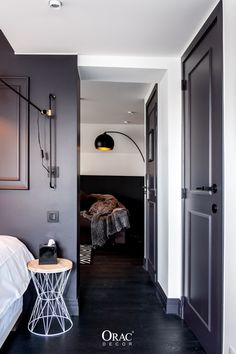 a bedroom with dark wood floors and white walls, along with a metal stool in front of the bed