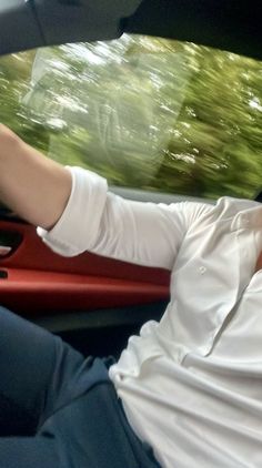 a man sitting in the driver's seat of a car with his hand on the steering wheel