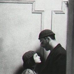 a man and woman standing next to each other in front of a wall with the door open