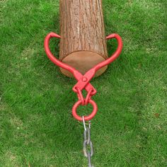 a log with chains attached to it sitting in the grass next to a pair of pliers