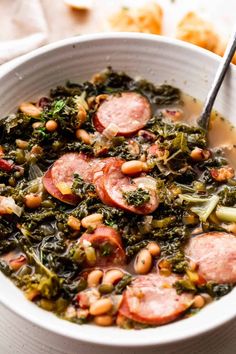 a white bowl filled with sausage, beans and greens