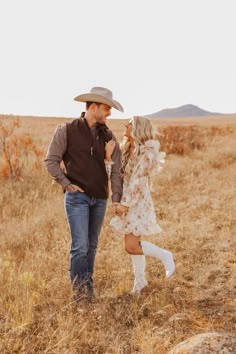 a man and woman holding hands in an open field