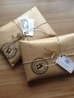 two wrapped presents tied with twine on top of a wooden table next to each other