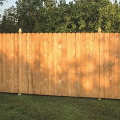 a wooden fence with grass and trees in the background