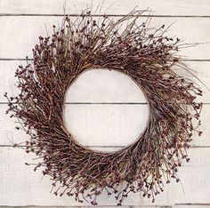 a dried wreath is hanging on a white wooden wall with the word love written in it