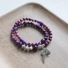 This beautiful gemstone rosary bracelet features Amethyst beads as the paters and purple aquaterra beads as the aves. Each of our stretch and wrap rosary bracelets is a full rosary. Each bracelet also includes a “bookmark” crucifix medal. This medal is moveable and can help you keep track of where you are at in your rosary as you pray throughout your day. Each bracelet is strung on durable elastic making it easy to stretch and wrap around your wrist without fear of snapping it. The medal accent Adjustable Purple Rosary Bracelet, Adjustable Purple Spiritual Rosary Bracelet, Adjustable Purple Rosary Bracelet With 8mm Beads, Custom Jewelry Necklaces, Pearl Rosary, Rosary Bracelet, Gifts Under 10, Amethyst Beads, Rosary