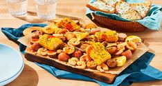 corn on the cob with potatoes and shrimp is served in a wooden platter