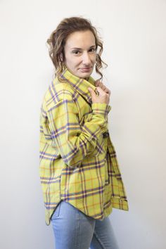 a woman is posing for the camera wearing a yellow plaid shirt and jeans with her hands in her pockets