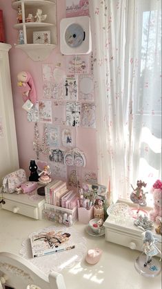 a white desk topped with lots of toys and decor next to a wall covered in pictures