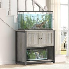 a fish tank sitting on top of a wooden cabinet next to a stair case in a house