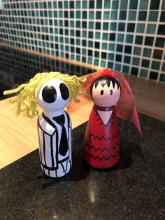 two wooden dolls sitting on top of a counter