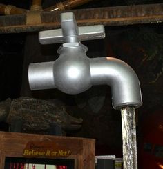 a metal faucet that is on top of a wooden shelf next to other items