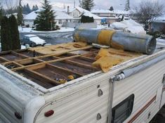 an old camper trailer is being worked on with wood and pipes attached to the roof