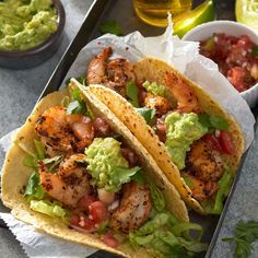 two shrimp tacos with guacamole and salsa