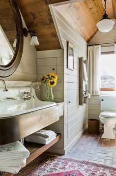 a bathroom with a sink, toilet and mirror in it's corner next to a window