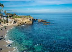 people are swimming in the ocean next to a beach