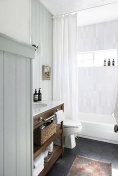 a bathroom with a toilet, sink and bathtub next to a window in it