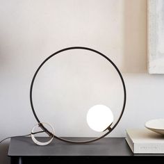 a table with a lamp on top of it next to a book and bowl in the corner