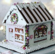 a white gingerbread house decorated with pink and gold decorations