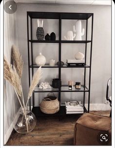 a shelf with vases, books and other items on it in a living room