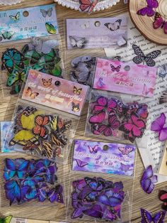 many different colored butterflies are on the table next to some cards and doilys