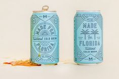 two cans of made in florida beer on a white surface with spilled gold flakes