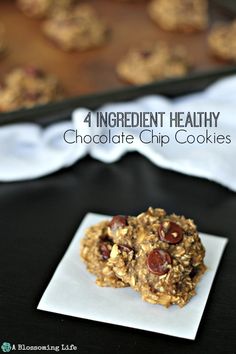 chocolate chip cookies are stacked on top of each other in front of a baking sheet