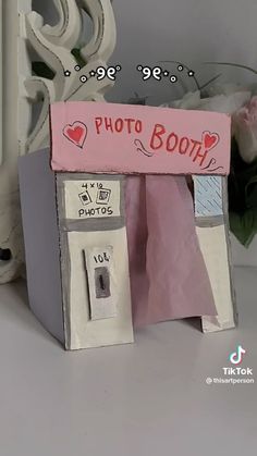 a photo booth made out of toilet paper with flowers in the background and a pink sign that says photo booth