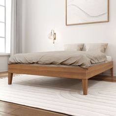 a bed sitting on top of a wooden floor next to a white rug and window