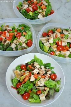 four white bowls filled with salad on top of a table