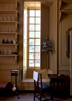 an empty room with shelves filled with wine glasses and other items on the wall next to a window