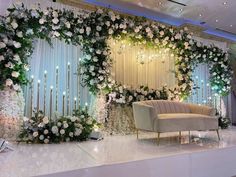 an elegant wedding setup with white flowers and greenery on the wall, chandelier and couch