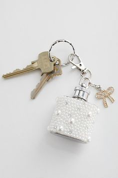 a keychain with a bottle and keys attached to it on a white surface