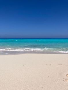 an empty beach with blue water and white sand