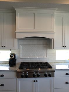 a stove top oven sitting inside of a kitchen next to white cabinets and counter tops