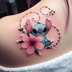 a woman with a tattoo on her shoulder has a pink flower in the shape of a cartoon character