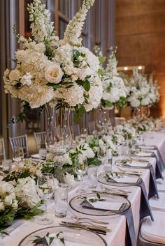 a long table is set with white flowers and place settings for the guests to sit at