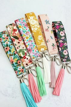 six key chains with tassels and flowers on them