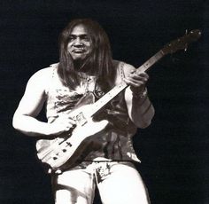 a man with long hair playing an electric guitar in front of a microphone and wearing white shorts