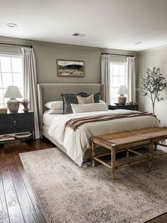 a large bed sitting in the middle of a bedroom next to two lamps and windows