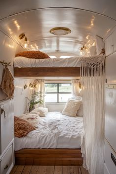 a white bed sitting inside of a bedroom next to a window with lights on it