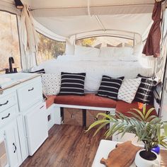 the interior of a camper with white walls and wood flooring is decorated in black and white